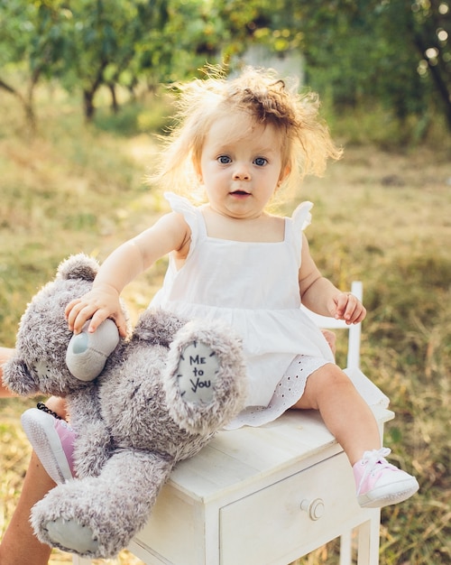 Foto gratuita niña pequeña con un vestido y un oso de peluche