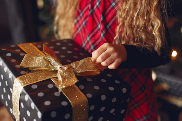 Niña de pie cerca del árbol de Navidad con presente