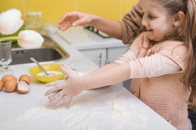 Niña de pie en la mesa con harina