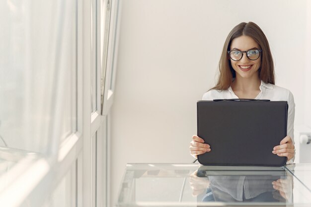 Niña de pie en la oficina con una computadora portátil