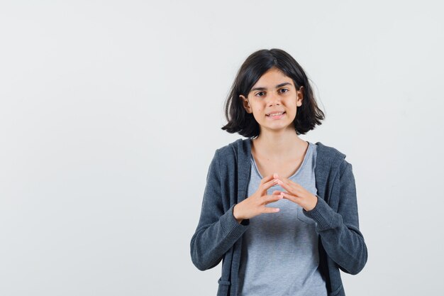 Niña de pie en pose de pensamiento en camiseta, chaqueta y aspecto sensible