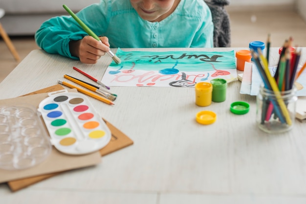 Niña pintando con acuarela en casa