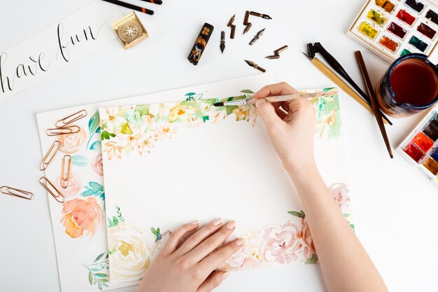 Niña pintando flores sobre papel con acuarela.