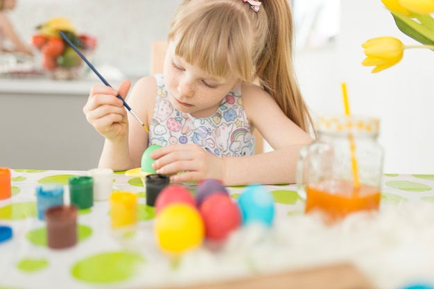 Niña pintando huevo con pincel