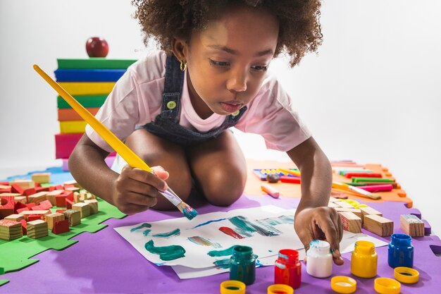 Niña pintando sobre papel en estudio