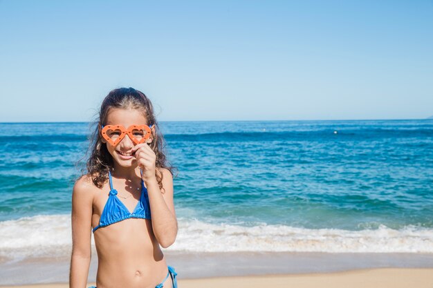 Niña en la playa feliz con sus gafas de nadar