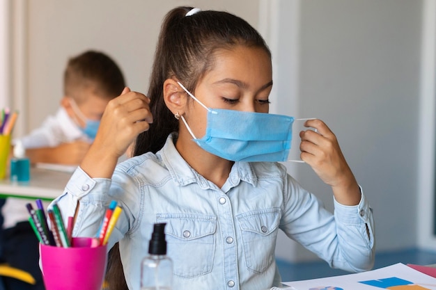 Niña poniéndose una mascarilla