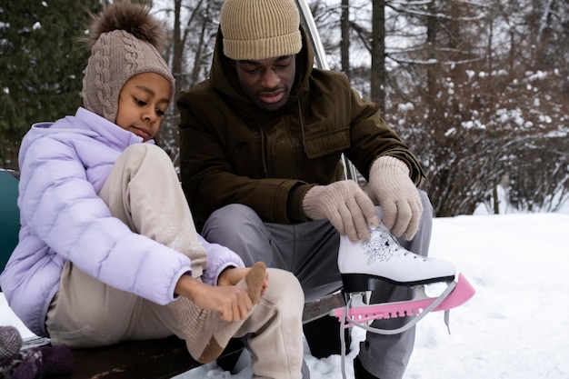 Foto gratuita niña poniéndose sus patines de hielo con la ayuda de su padre