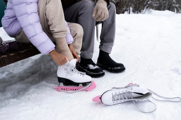 Niña poniéndose sus patines de hielo con la ayuda de su padre