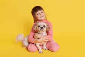 Foto gratuita niña posando con perro pequinés en amarillo