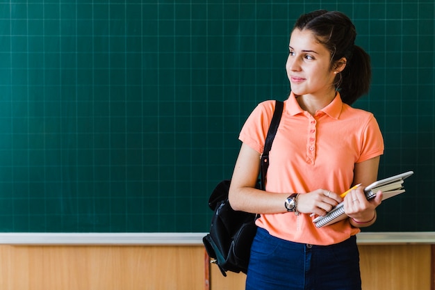 Niña posando con la pizarra en el colegio