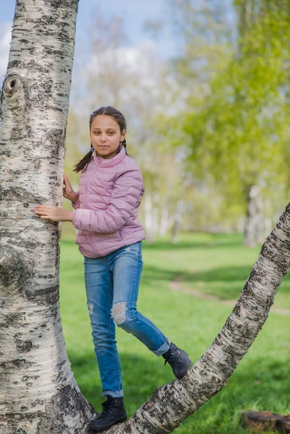 Niña posando en el tronco de un árbol