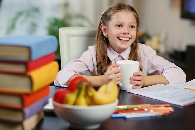 Niña positiva bebe té matutino antes de estudiar.