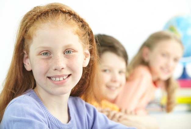 Foto gratuita niña positiva con compañeros de clase de fondo