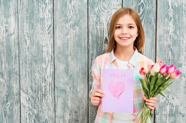 Niña con postal del día de la madre y tulipanes.