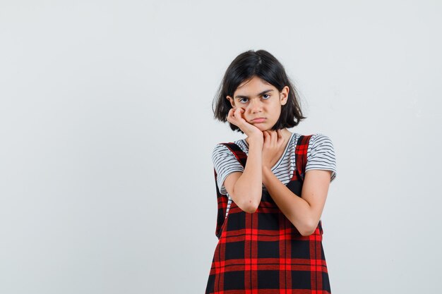 Niña preadolescente con la mano en la mejilla en camiseta