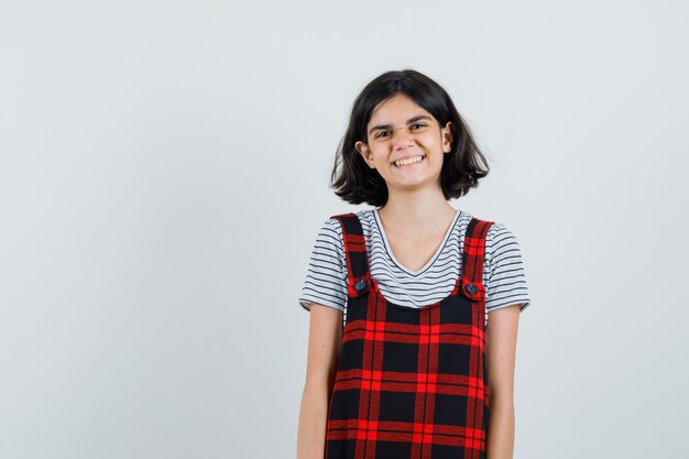 Niña preadolescente sonriendo en camiseta, mono y mirando alegre. vista frontal. espacio para texto