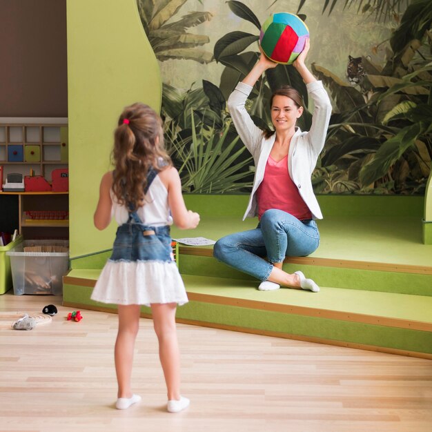 Niña y profesor de tiro completo jugando juntos