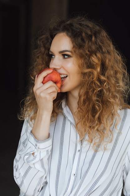 La niña prueba una manzana con una sonrisa.