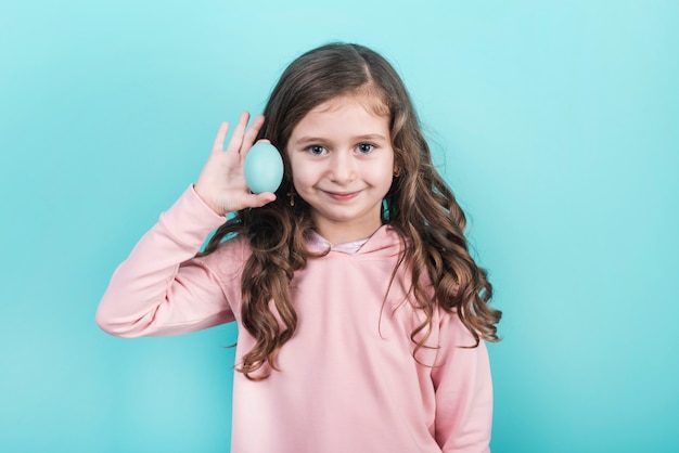 Niña que sostiene el huevo de Pascua azul