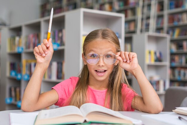 Niña que tiene una idea en la biblioteca