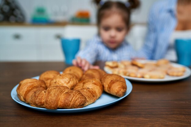 Niña quiere tomar croissant en la cocina