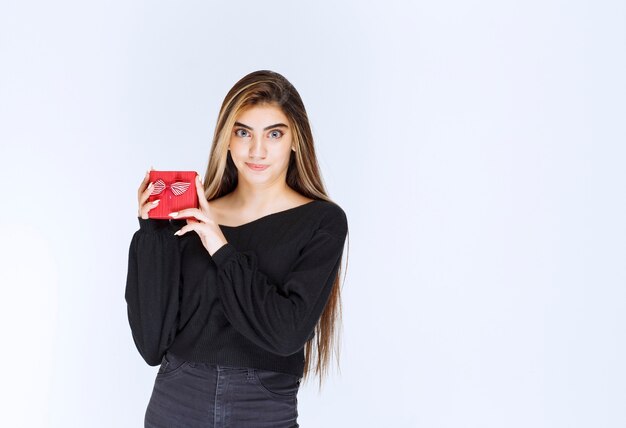 La niña recibió una caja de regalo roja y se sintió feliz. Foto de alta calidad