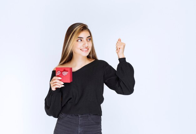 La niña recibió una caja de regalo roja y se sintió feliz. Foto de alta calidad