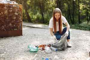 Foto gratuita niña recoge basura en bolsas de basura en el parque