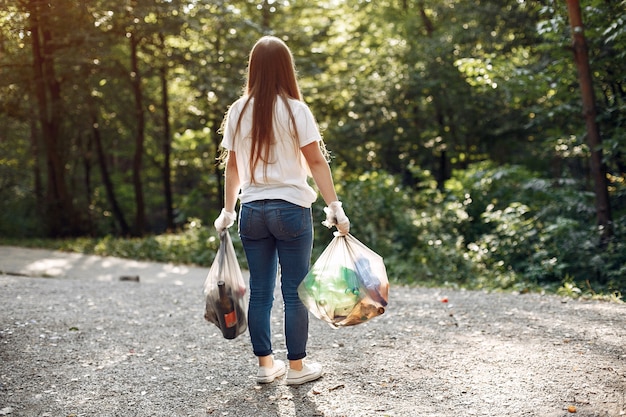 Niña recoge basura en bolsas de basura en el parque