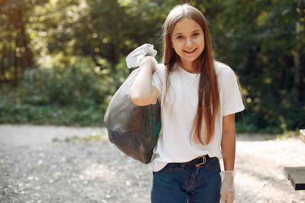 Niña recoge basura en bolsas de basura en el parque