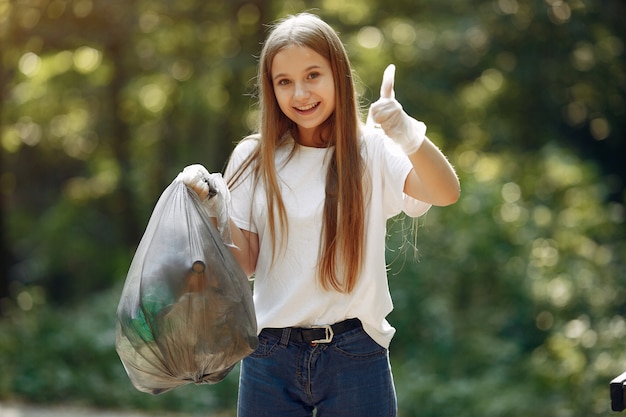 Niña recoge basura en bolsas de basura en el parque