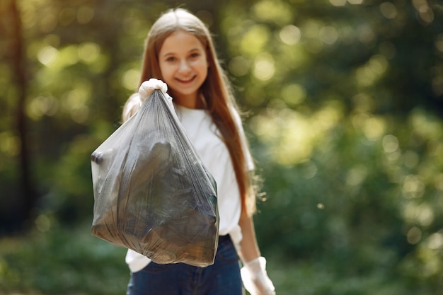 Niña recoge basura en bolsas de basura en el parque