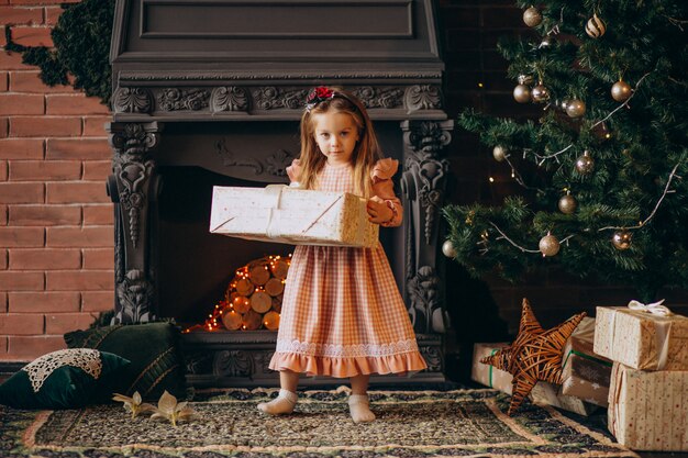 Niña con regalos de arbol de navidad.