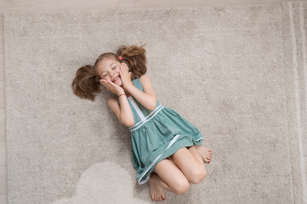 Niña relajada tirada en el suelo en el interior y sonriendo