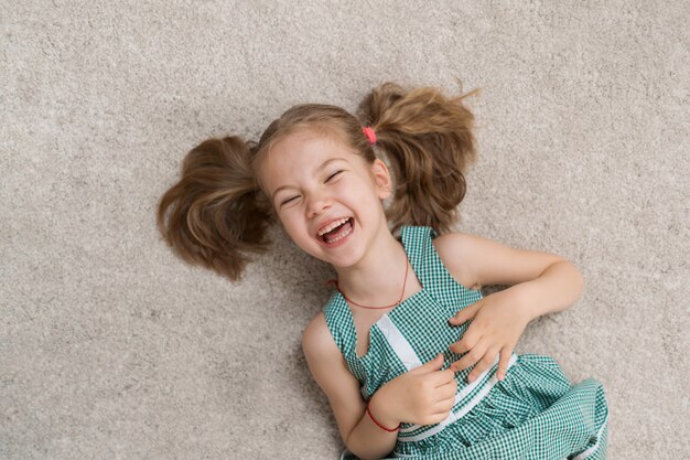 Niña relajada tirada en el suelo en el interior y sonriendo