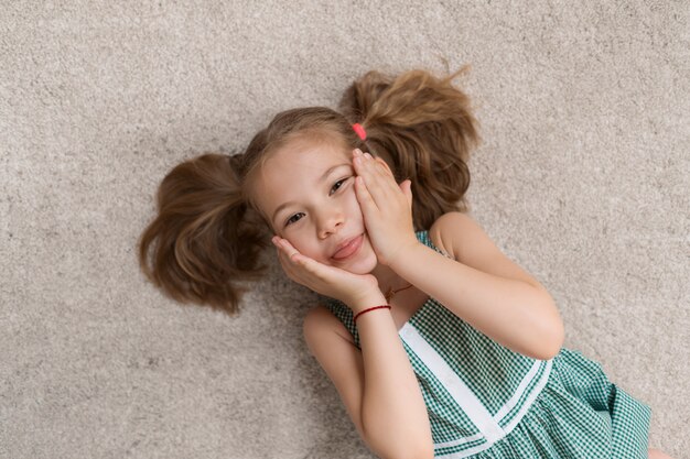 Niña relajada tirada en el suelo en el interior y sonriendo