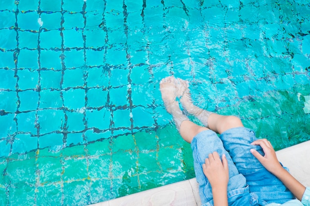 La niña relajante pies con agua en la piscina.