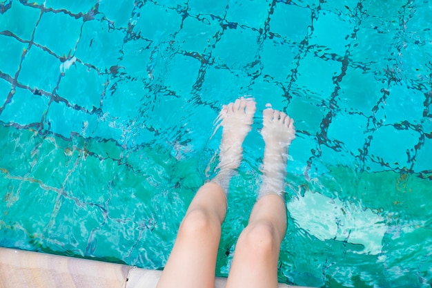 La niña relajante pies con agua en la piscina.