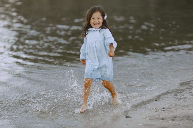 Niña en el río. Chica salpica agua. Chica con un vestido azul.