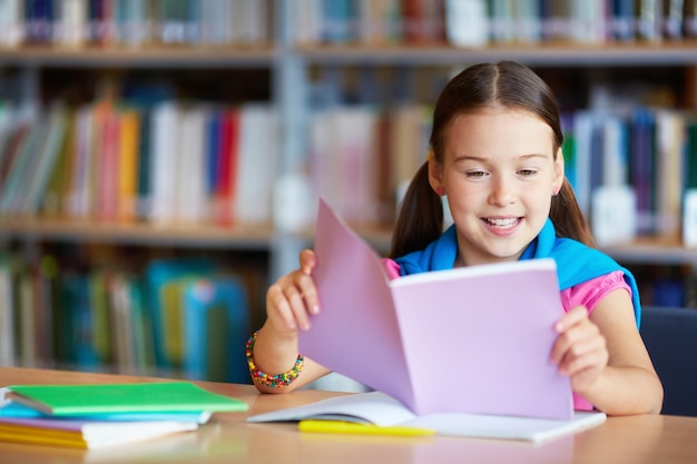 Niña rodeada de libros en la biblioteca