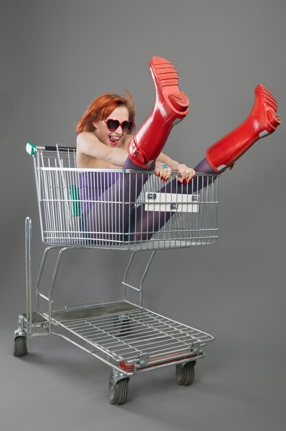 Niña roja montando en un carrito de la compra