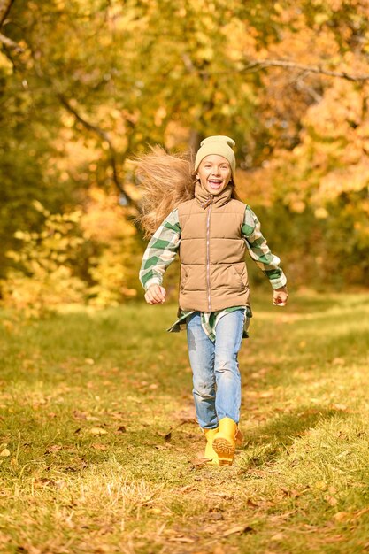 Una niña en ropa de abrigo jugando en el parque.