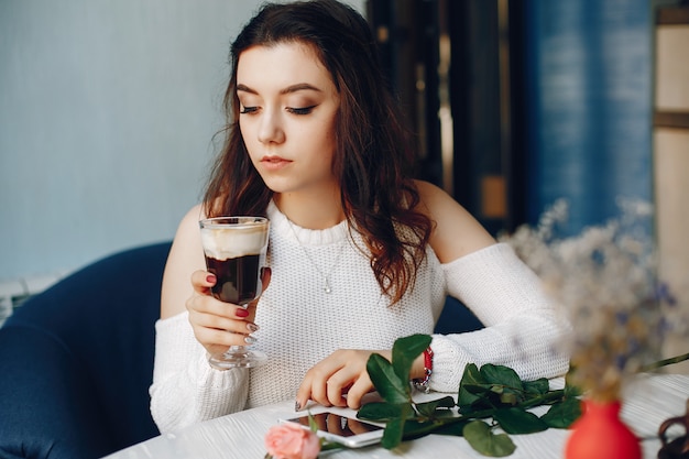 Una niña con la rosa y el postre en la cafetería