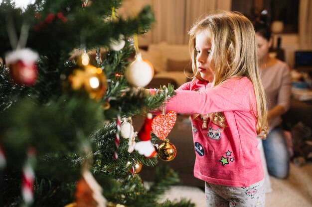 Niña rubia decorando árbol de navidad