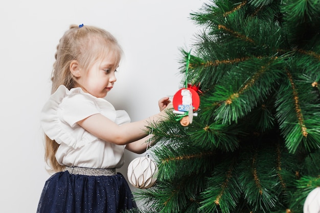 Niña rubia decorando árbol de navidad