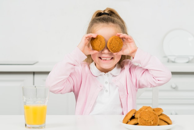 Niña rubia con galletas y zumo de naranja