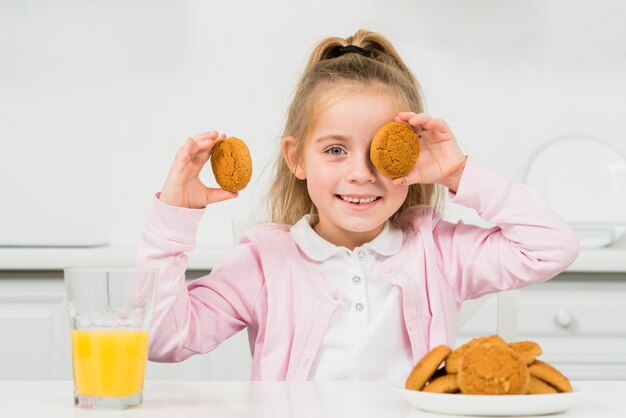 Niña rubia con galletas y zumo de naranja