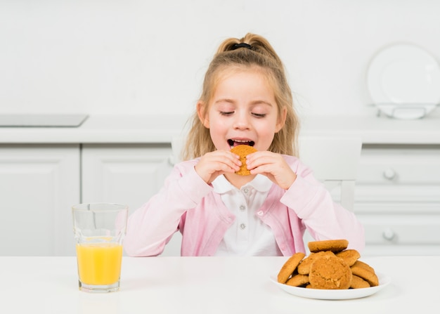 Niña rubia con galletas y zumo de naranja