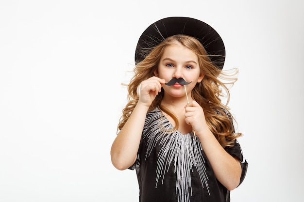 Niña rubia con ojos azules. Posando con máscara de bigote.